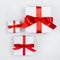 Different bright simple white gift box with red silk ribbon on white wooden table, top view, square.