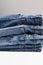 Different classic jeans background. A stack of folded jeans on white table with copy space