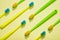 Different colors kids toothbrushes, green and yellow on a yellow background