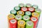 Different colours of batteries on white background. Close up of positive ends batteries, selective focus. Used battery for