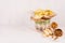 Different crispy golden snacks in wicker basket and paper cones on soft white wood background, with copy space.