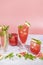 Different elegant glasses with watermelon cocktail. Splash, splatter, water drops on the pink background