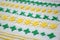 Different examples of green and yellow patterns of embroidery on white fabric