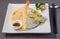 Different fish and vegetables tempura with citrus fruit sauce on daikon julien