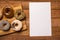Different flavoured doughnuts on wooden board with white paper for copy space