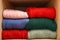 Different folded warm sweaters on wooden shelf