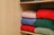 Different folded warm sweaters on wooden shelf