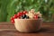 Different fresh ripe currants in bowl on wooden table outdoors, closeup