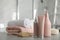Different hair care products, towels and brush on table in bathroom