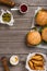 Different hamburger on wooden table with sauces, fries and pickl