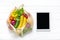 Different health food - yellow bell pepper, tomatoes, bananas, lettuce, green, cucumber, onions in mesh bag tablet with black touc