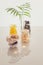 Different kind of vitamins in glass bottles, palm leaves and lighting garland on a light background