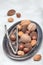 Different kinds of nuts in the shell: hazelnut, walnut, almond and brazil nuts on plate with nut cracker on background, vertical