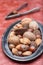 Different kinds of nuts in shell, hazelnut, walnut, almond and brazil nuts on plate with nut cracker on background, vertical