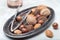 Different kinds of nuts in shell, hazelnut, walnut, almond and brazil nuts on plate with nut cracker, horizontal