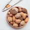 Different kinds of nuts in shell, hazelnut, walnut, almond and brazil nuts in  wooden bowl, square format, top view