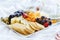 Different kinds of wine snacks: cheeses, crackers, fruits and olives on white table