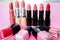 Different lipsticks and nail polishes on color background. Professional cosmetic