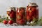 Different marinated tomatoes in jars for the winter on a light gray background