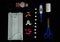 Different medicine pills, tablets and capsules, thermometer and scissors, bandage, medical mask, alcohol gel on a dark background.