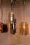 Different modern streamlined mirror copper chandeliers. Cylindrical metal copper shade pendant