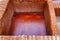 Different old stone vats with red dye for leather at Tannery of Tetouan Medina.