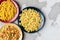 Different pasta on red, yellow and blue plates on a cement background