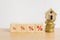 Different size of percent sign on wood cubes, miniature house on stack of coins on wooden desk