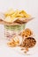 Different spicy mexican snacks in basket and paper cone on white wooden board, closeup.