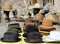 Different style men hats on a shelf of a street market. On background, manikin heads wearing straw hats