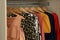 Different stylish party dresses on hangers in wardrobe, closeup
