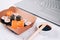 Different sushi rolls with salmon in delivery paper box on white marble table background with laptop - futomaki, uramaki