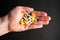 Different tablets, pills in hand, medications drugs on black background