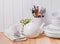 Different tableware, plates, cups standing near the white wooden wall