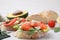Different tasty bruschettas and ingredients on light grey textured table, closeup