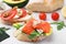 Different tasty bruschettas and ingredients on light grey textured table, closeup