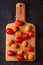 Different tomato cultivars on a wood board on the black background. top view