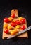 Different tomato cultivars on a wood board on the black background. top view