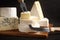 Different types of cheese, knife and fork on black table, closeup