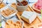 Different types of cheeses, wines, baguettes, fruits and snacks on the table for tasting and holiday scenery