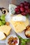 Different types of delicatessen Cheeses with grapes, bread and walnuts on the slate background