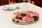 Different types of raw beef with fresh herbs and vegetables on the table for customer selection