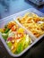 Different types of takeaway food in microwavable containers on a wooden background.