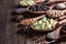 Different types of whole Indian spices in wooden spoons on rustic background