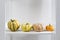 Different varieties of pumpkins lie on white shelf of the rack in the kitchen interior