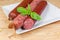 Different varieties of sausages on white square dish close-up