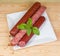 Different varieties of sausages on white square dish, top view