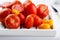 Different varieties of tomatoes on a white tray. Colorful red and yellow fresh ripe tomatoes