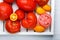 Different varieties of tomatoes on a white tray. Colorful red and yellow fresh ripe tomatoes. Top view