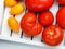 Different varieties of tomatoes on a white tray. Colorful red and yellow fresh ripe tomatoes. Top view